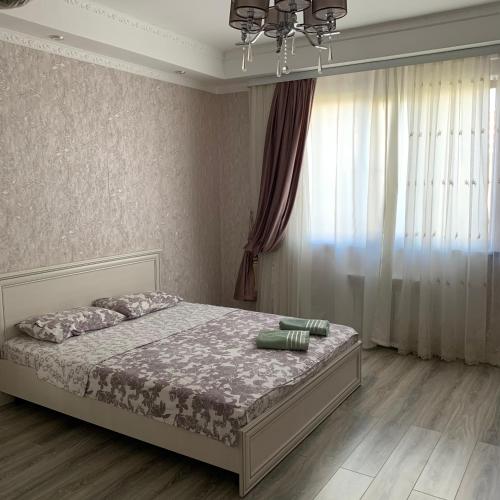 um quarto com uma cama e uma grande janela em Apartment Vefa Bishkek em Bishkek