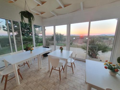 una sala da pranzo con tavoli e sedie bianchi e finestre di Villa Elios Guesthouse a Birgi Vecchi