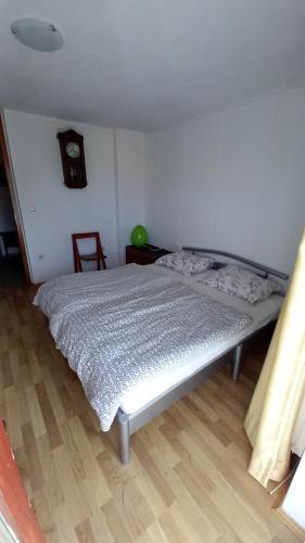1 cama en un dormitorio con reloj en la pared en Draga - 2 bedroom apartment, en Tržič