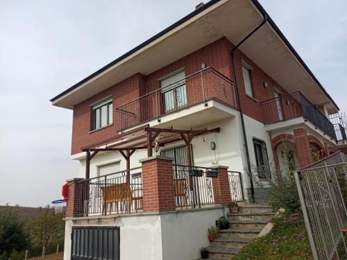 a red brick house with a balcony and stairs at Casa Bellavista in Neive