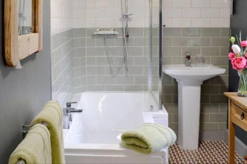 Woodbank Cottage Newton Stewart في نيوتن ستيوارت: حمام مع حوض استحمام ومغسلة
