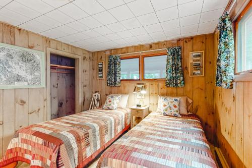 2 camas en una habitación con paredes y ventanas de madera en Haven on Spindle Point, en Meredith