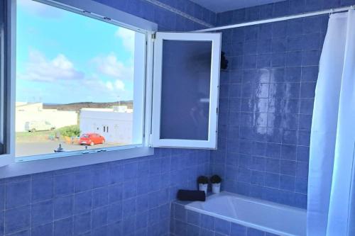 ein blau gefliestes Bad mit einer Badewanne und einem Fenster in der Unterkunft Casa Mar y Lava in El Golfo