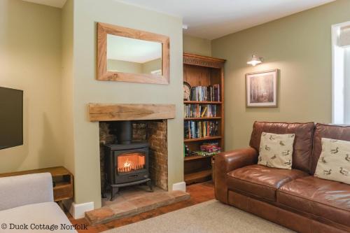 a living room with a couch and a fireplace at Duck Cottage - Grade II Listed cottage, village location, nr Holt in Letheringsett