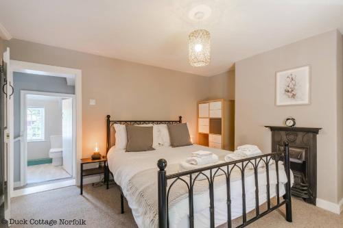 a bedroom with a large bed and a fireplace at Duck Cottage - Grade II Listed cottage, village location, nr Holt in Letheringsett