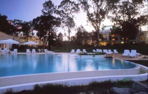 a large swimming pool with white chairs and tables at Green Park in Punta del Este