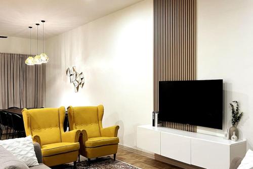 Lapan Ompek Homestay 3 Bedrooms في نيلاي: غرفة معيشة فيها كرسيين اصفر وتلفزيون