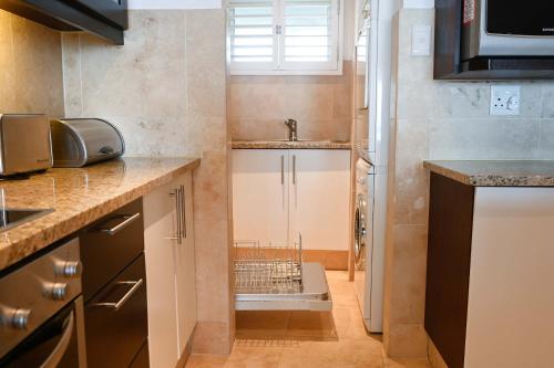 a small kitchen with a sink and a dishwasher at Surfside Ballito - Family Only in Ballito