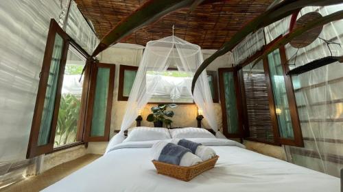 a bedroom with a large white bed with windows at The Baobab Resort in Sam Roi Yot