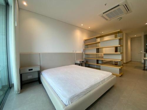 een slaapkamer met een wit bed en een boekenplank bij Apartaestudio Amoblado - Distrito90 in Barranquilla