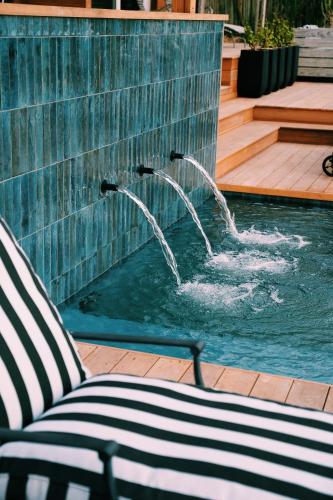 a pool with a chair and a water fountain at The Oyster Box Beach House by The Oyster Collection in Kenton on Sea