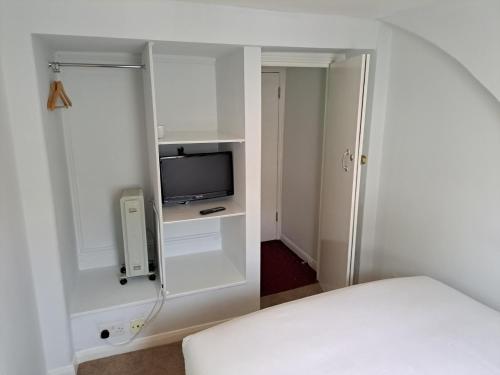 um quarto branco com uma cama e uma televisão em Palace Court Hotel em Londres