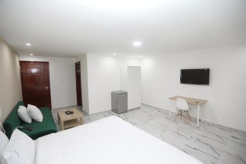 a white bedroom with a bed and a tv at MJI GROUP in Tan-Tan