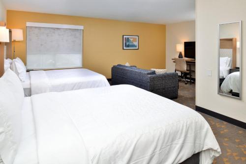 a hotel room with two beds and a couch at Holiday Inn Hotel & Suites Overland Park-Convention Center by IHG in Overland Park