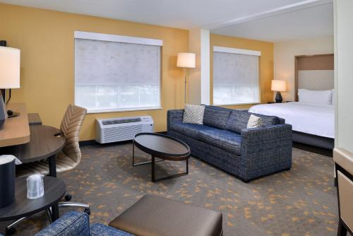 オーバーランド・パークにあるホリデイ イン ホテル＆スイーツ オーバーランド パーク - コンベンション センターのベッド、ソファ、椅子が備わるホテルルームです。