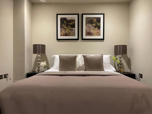 a bedroom with a large bed with two lamps at High End 1 BR Apt, 2 Beds Desirable Chigwell in Chigwell