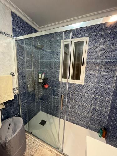 y baño con ducha de azulejos azules. en Maison Orihuela Costa, en Orihuela