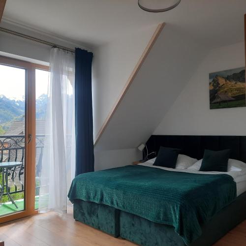 a bedroom with a bed and a large window at Willa Grand Krzesanica in Kościelisko