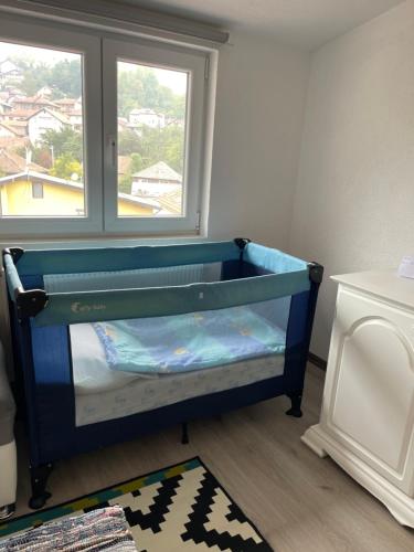 a blue crib in a room with a window at Apartman Maki in Sarajevo