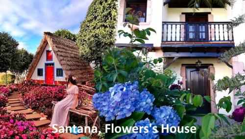 a woman walking in front of a house with flowers at Santana, Flowers's House in Santana