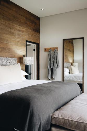 a bedroom with a large bed and two mirrors at The Oyster Box Beach House by The Oyster Collection in Kenton on Sea