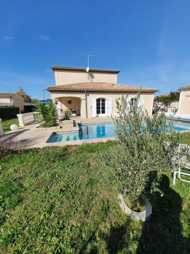 a villa with a swimming pool in front of a house at La Bastide du Canal avec piscine et clim in Carcassonne