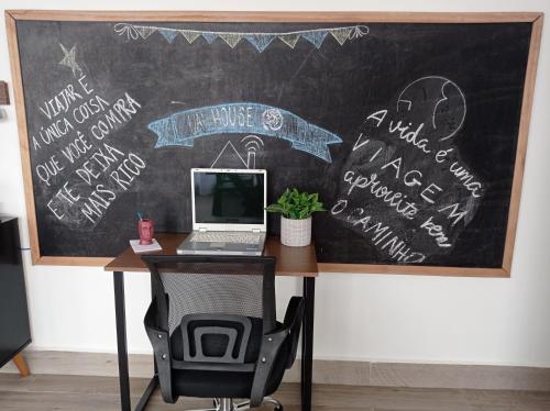 a laptop computer sitting on a desk with a chalkboard at Uai House com jacuzzi, teto rooftop retrátil e colchão massageador in Poços de Caldas