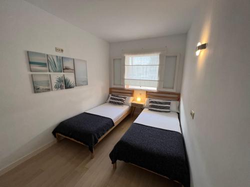 twee bedden in een kleine kamer met een raam bij Apartment Puerto ALCUDIA in Port d'Alcudia