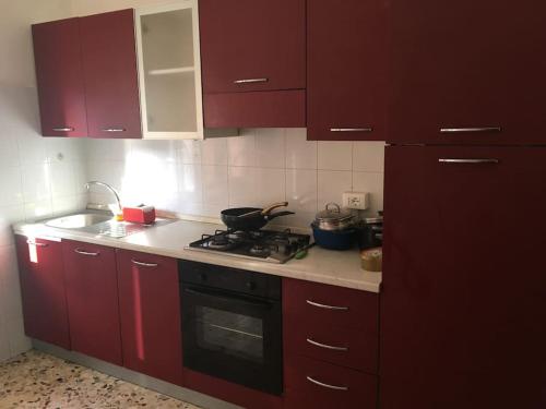 a kitchen with red cabinets and a stove top oven at Appartamento relax a Catanzaro Lido in Catanzaro