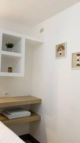 a white room with a bed and a shelf with plants at Curious Family Space D1 in Guatemala