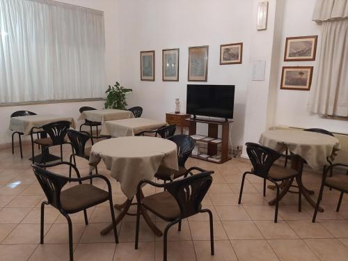 a room with tables and chairs and a television at Hotel Cucciolo in Donoratico