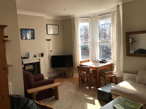 uma sala de estar com um sofá, uma mesa e uma televisão em Elegant 3bed Crouchend in style with roof terrace em Londres