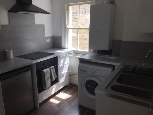 a kitchen with a washing machine and a window at Elegant 3bed Crouchend in style with roof terrace in London