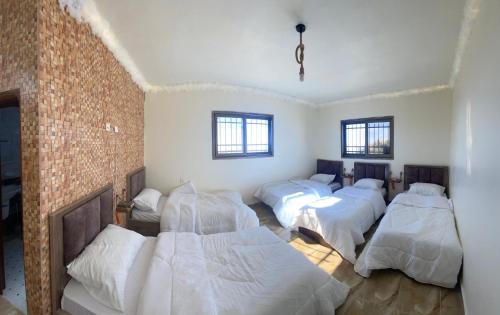 a room with four beds and a brick wall at Nabati hostel in Wadi Musa