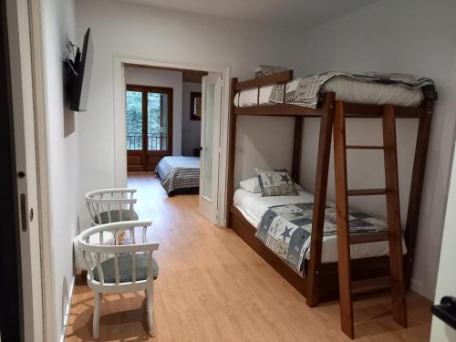 a bedroom with two bunk beds and a chair at Apartamentos CAN GUSI in Ribes de Freser