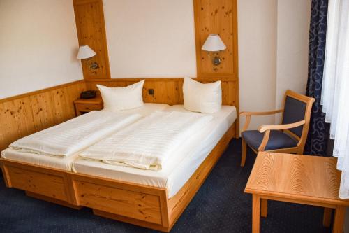 ein Schlafzimmer mit einem Holzbett mit einem Stuhl und einem Tisch in der Unterkunft Hotel Bergwiesen - Zimmer mit Balkon oder Terasse in Lohr