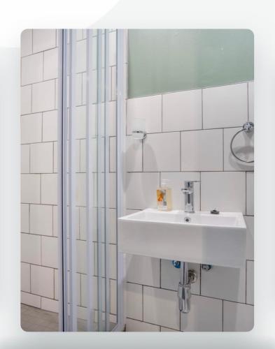 uma casa de banho com um lavatório e um chuveiro em Batchelor City Studio Apartment em Durban