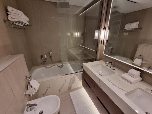 a bathroom with a sink and a tub and a toilet at Shaqa at Address Beach Residence - Fuj in Fujairah
