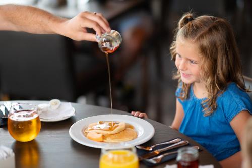 a little girl sitting at a table with a plate of pancakes at Rodd Miramichi in Miramichi