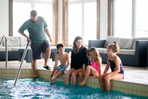 a family sitting on the edge of a swimming pool at Rodd Miramichi in Miramichi