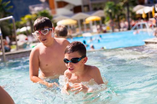 two boys in the swimming pool at a resort at Hotel Savoy Palace - Tonelli Hotels in Riva del Garda