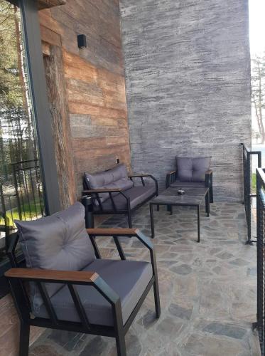 a patio with couches and tables and a brick wall at Вила Bora Vista 2 in Tsigov Chark