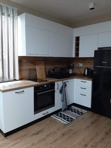 a kitchen with white cabinets and a black refrigerator at Вила Bora Vista 2 in Tsigov Chark