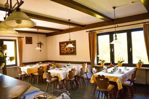 ein Esszimmer mit Tischen und Stühlen und Fenstern in der Unterkunft Hotel Bergwiesen - Zimmer mit Balkon oder Terasse in Lohr