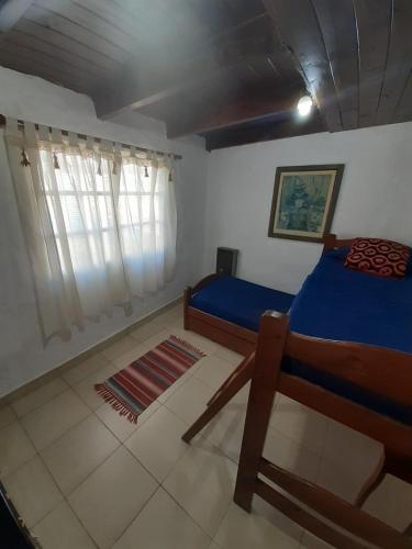 a bedroom with a blue bed and a window at Zorzales in Funes