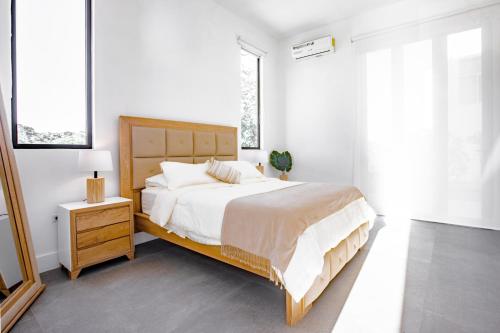ein weißes Schlafzimmer mit einem großen Bett und einem Nachttisch in der Unterkunft Ocean view luxury Villa, Private Pool 4BD 8PPL in Playa Venao