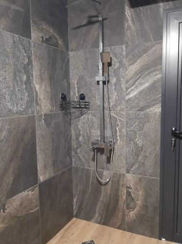 a shower in a bathroom with a stone wall at Вила Bora Vista 2 in Tsigov Chark