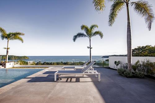 a patio with two chairs and palm trees next to a swimming pool at Ocean view luxury Villa, Private Pool 4BD 8PPL in Playa Venao