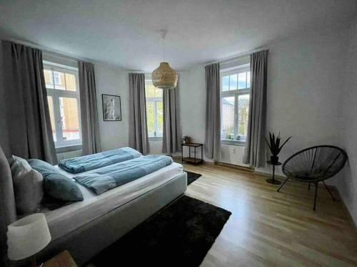 Schlafzimmer mit einem Bett mit blauer Bettwäsche und Fenstern in der Unterkunft Ein gemütlicher Platz im Gründerzeitviertel in Chemnitz