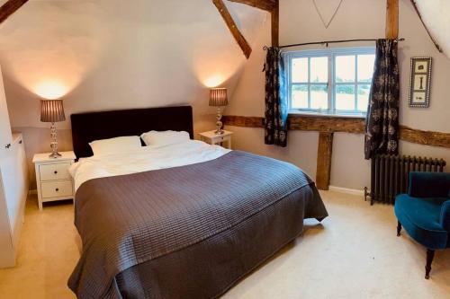 a bedroom with a large bed and a window at 2 Beds & living in our idyllic country Cottage in Bedford